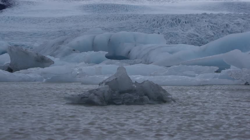 Water flying past some ice formations on the shore