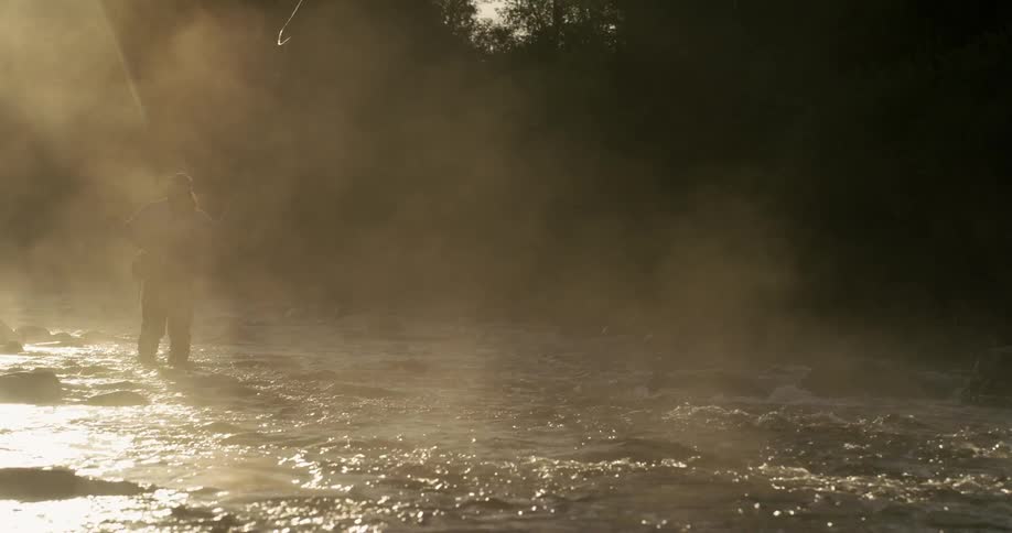 A fisherman casts a line in a moving river