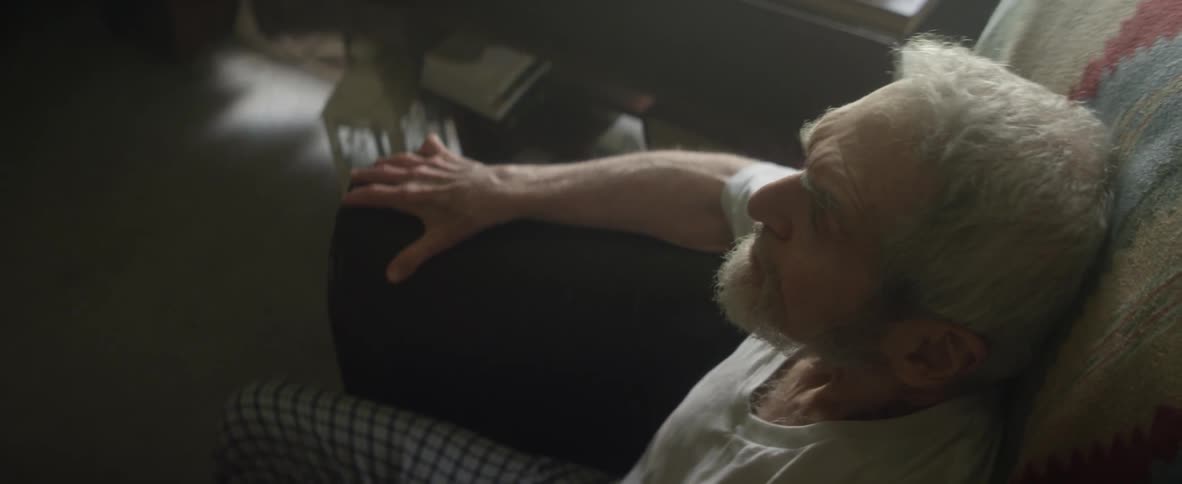 An elderly man sits down in a chair