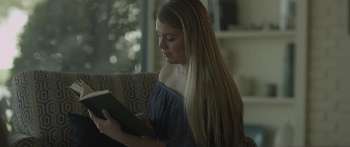 Woman sitting on chair in living room looking at a book