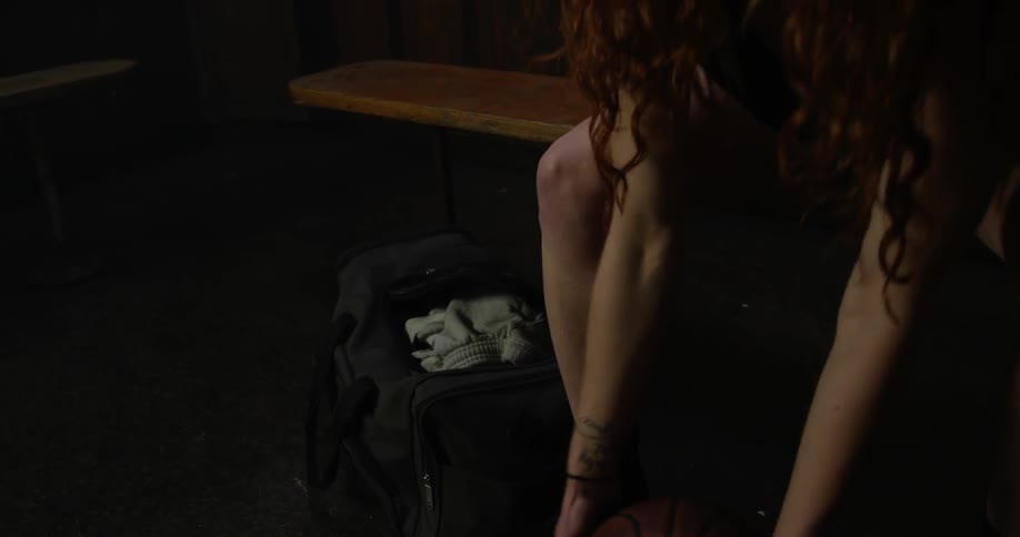 A woman packs her bag and grabs a basketball