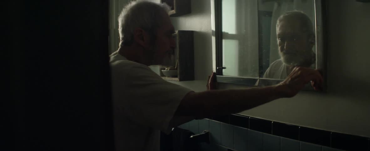 Man closes medicine cabinet and looks in mirror