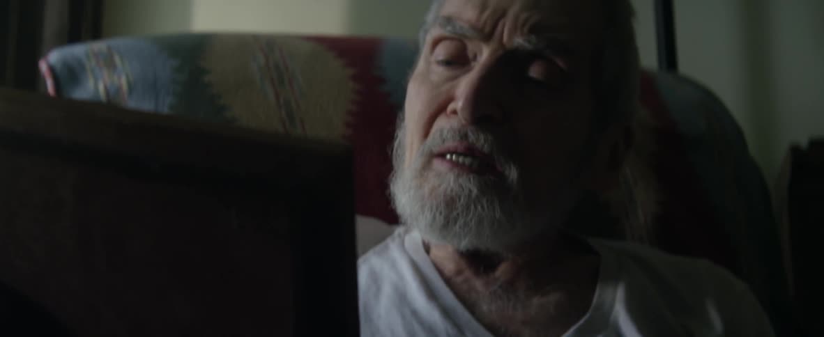 A man sits in a chair looking at a photo