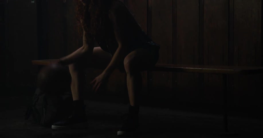 Woman sits on a bench and bounces a basketball