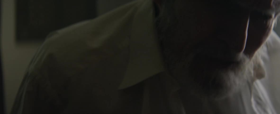 An elderly man is struggling to button his shirt