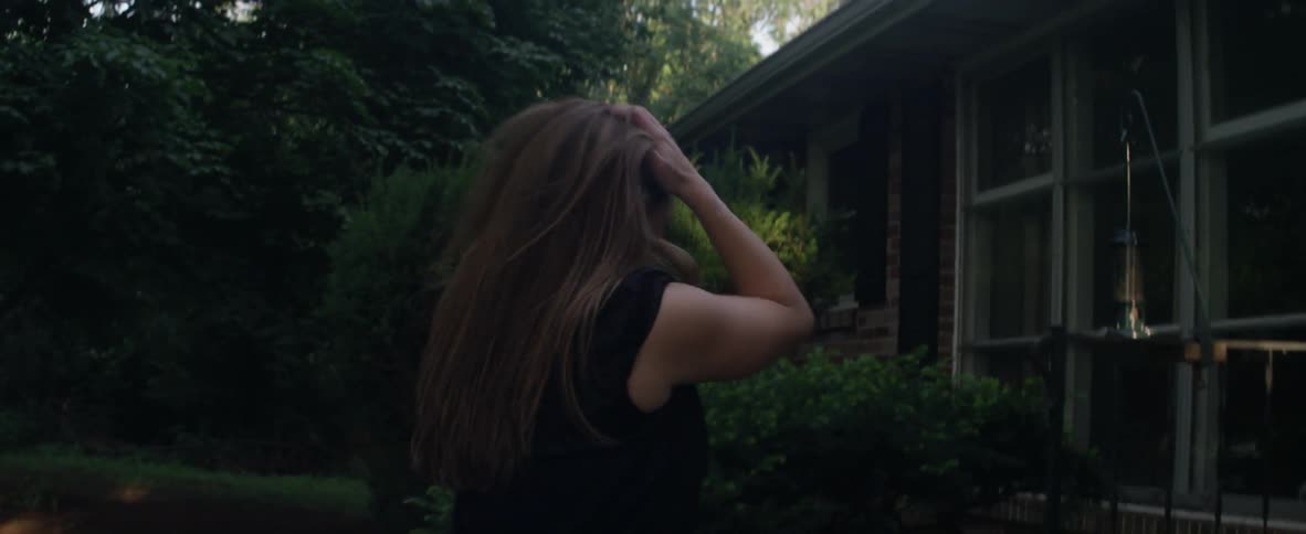 Woman fixing hair and clothes as she walks up to front door of house