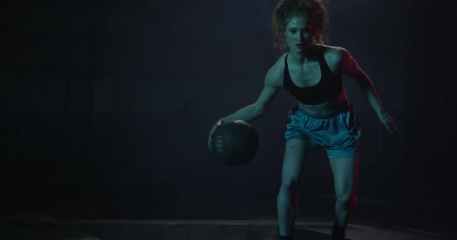 A woman dribbles a basketball between her legs