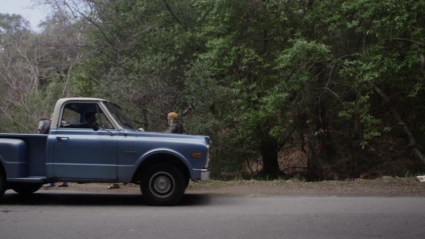An old pickup trucks pulls over for a group of people