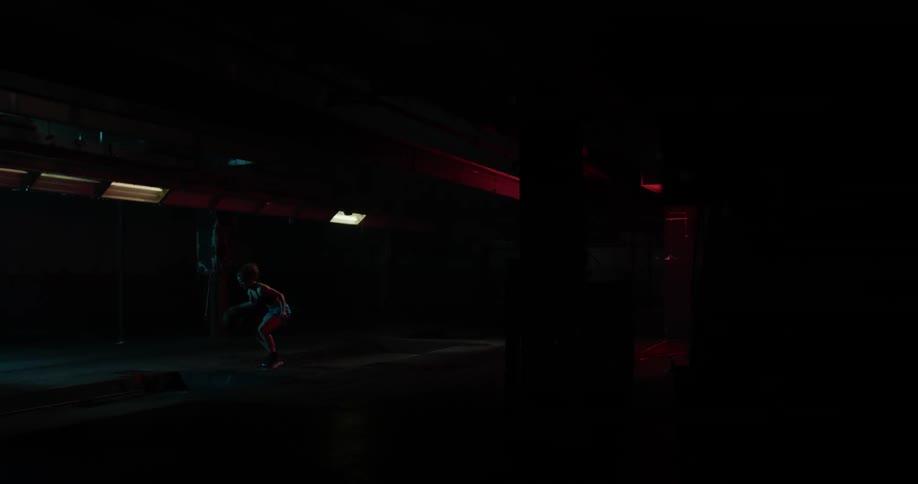A woman in the distance is bouncing a ball in the dark