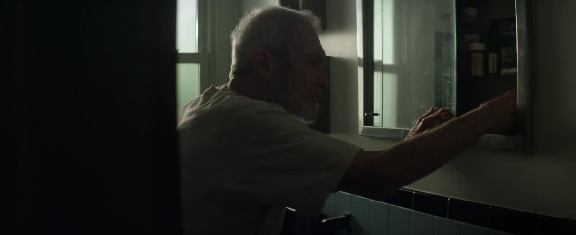 A man shakes as he opens a medicine cabinet