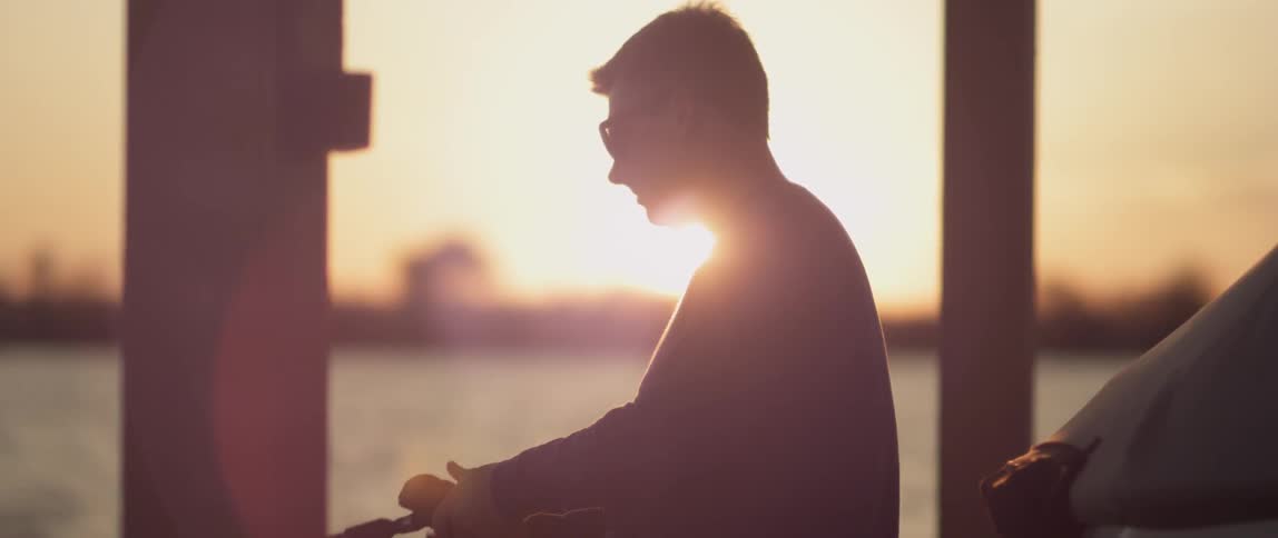 A man reels in his line and casts it