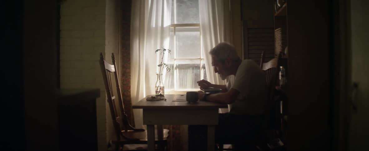 A man sits by his window eating
