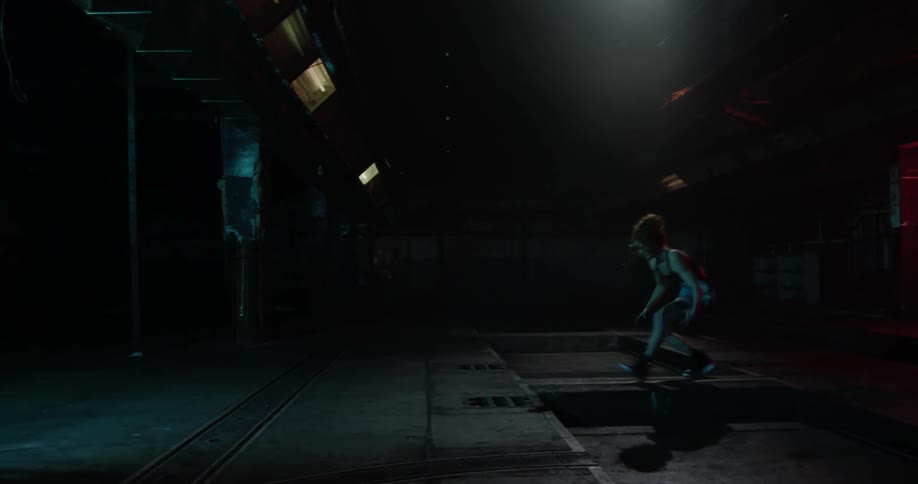 A woman is dribbling a basketball in a dark room by herself