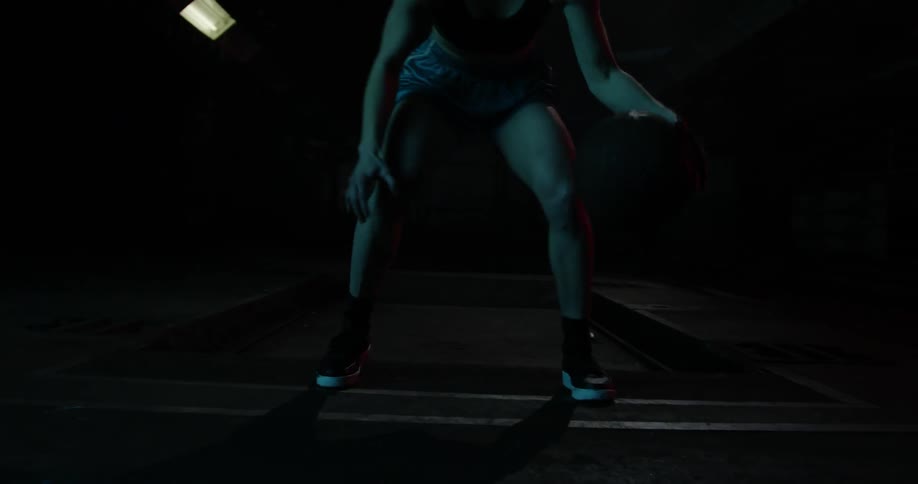 A woman dribbles a basketball between her legs