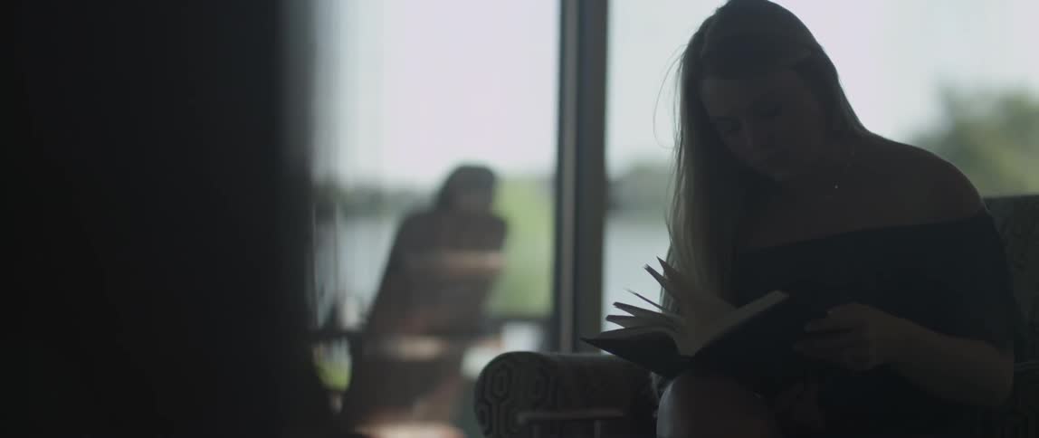 A woman is reading a book as she sits indoors