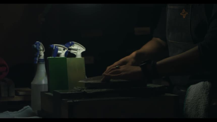 A man is sharpening a kitchen knife on a stone