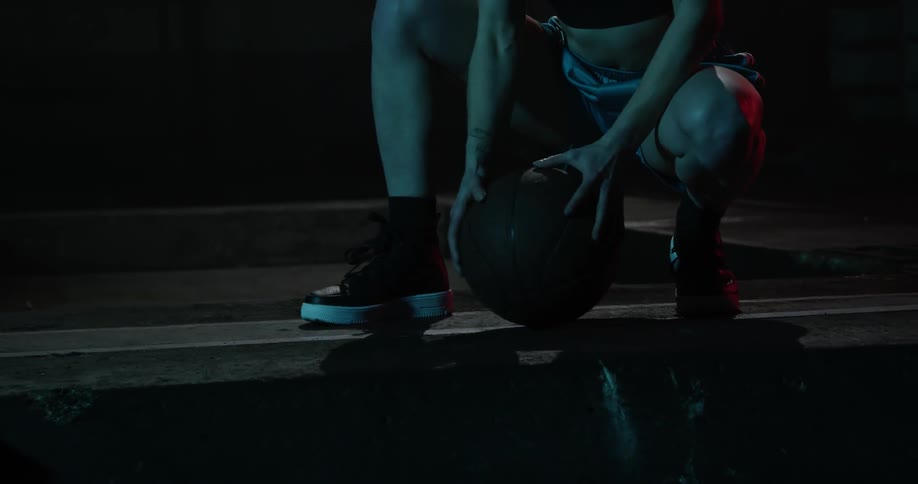 A woman rolls a basketball on the ground