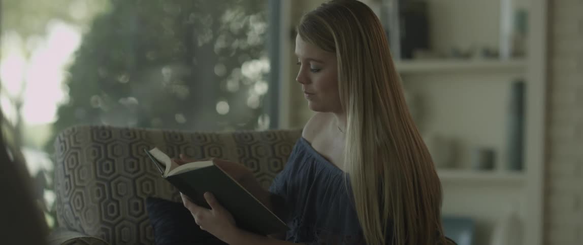 A girl with long hair is reading a book