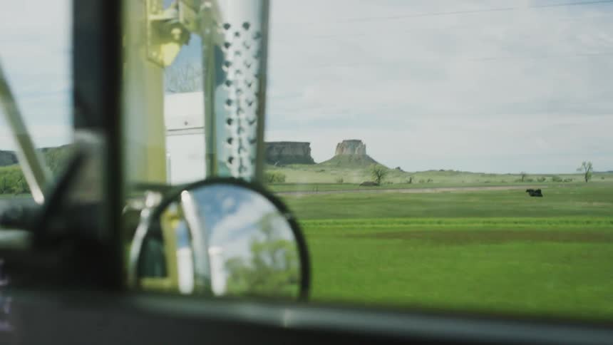 A truck drives past a green field