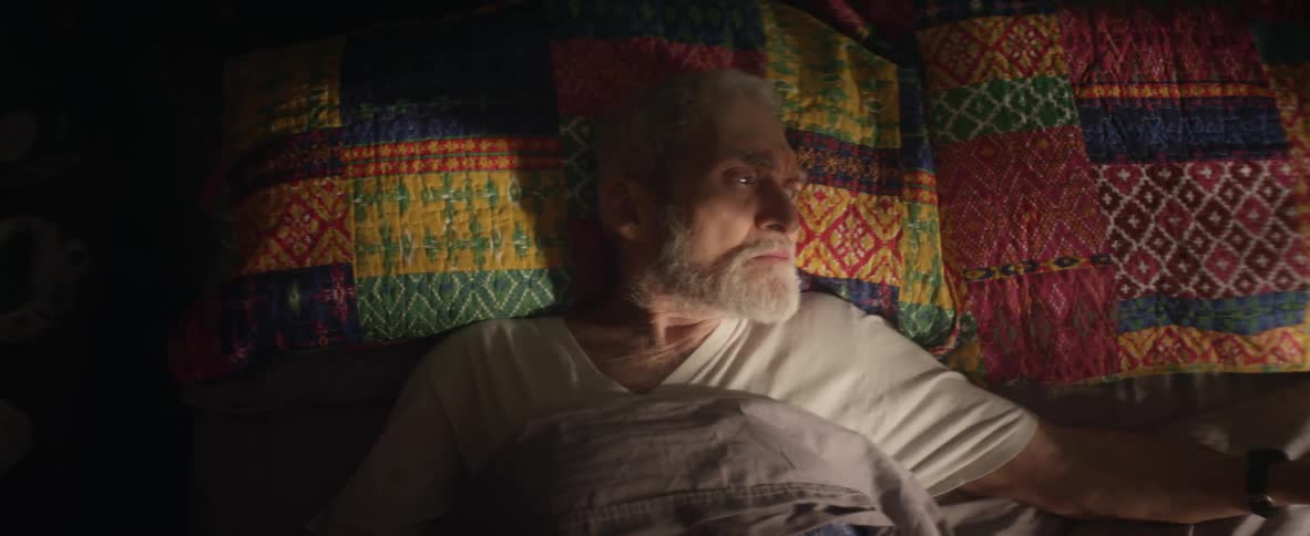 An elderly man lays in bed