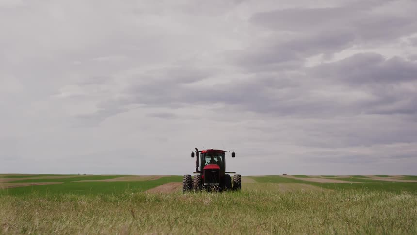 A tractor drives across a rural field