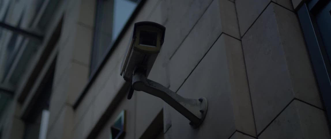A security camera is operating on the outside wall of a building
