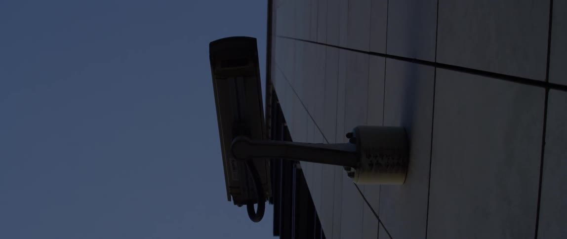 A security camera is operating on the outside wall of a building