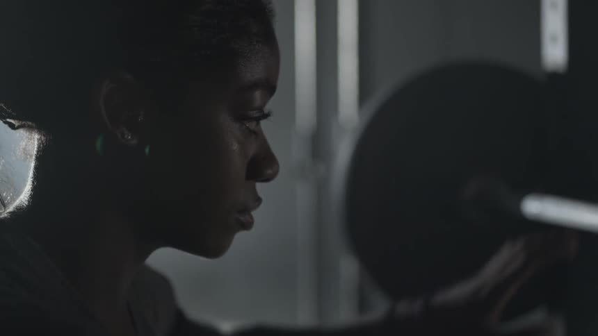 A woman talks as she removes her hand from a weight bar