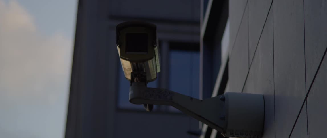 A security camera is attached to the exterior of a building