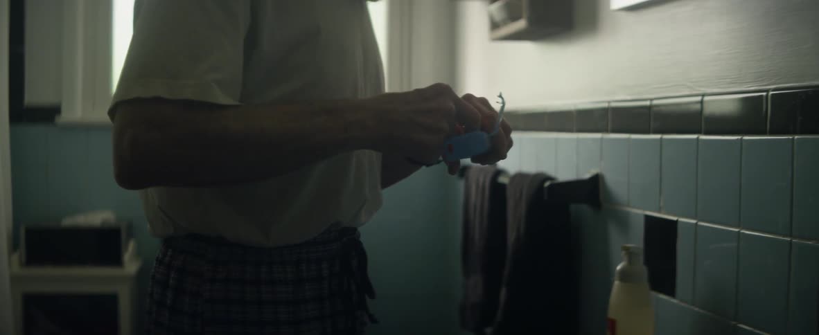 An elderly man opens a container in the bathroom