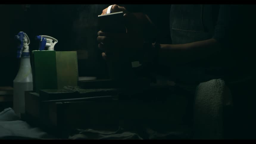 A carpenter sprays a wood block with a spray bottle