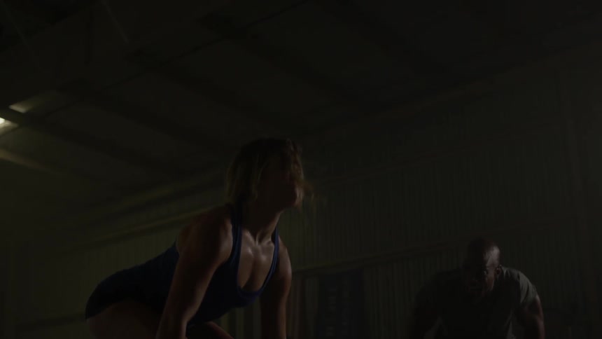 A woman lifts weights in a dark gym