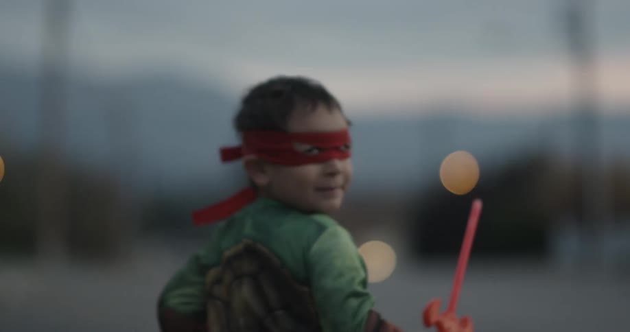 A child in costume runs outside while smiling