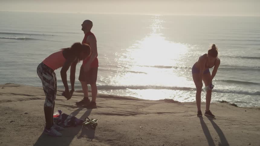 Three people stop to catch their breath on the beach