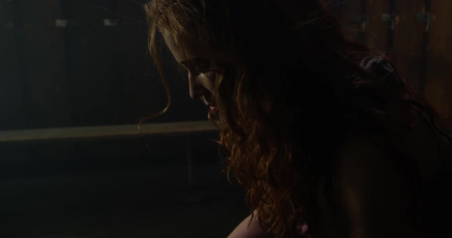 A woman sits in a dark locker room