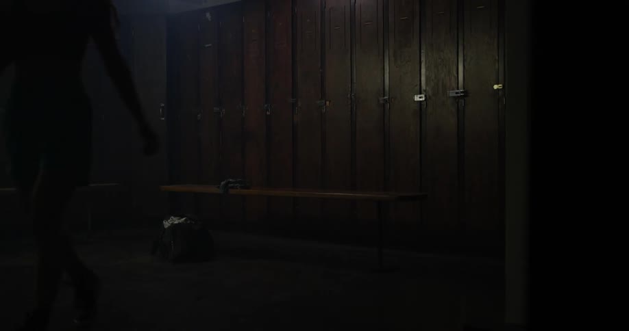 A woman stands up from a bench holding a basketball