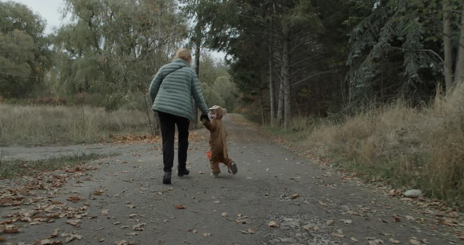A woman and toddler run down a path on halloween