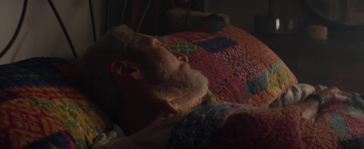An elderly man looks at the empty space beside him in bed