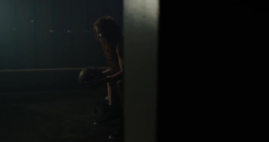 A woman sits thinking in a locker room