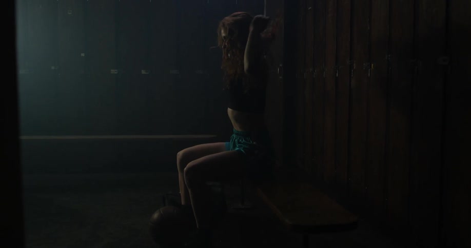A lady is taking off her clothes in a locker room
