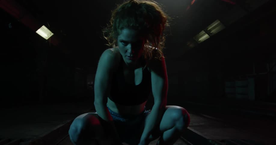 A woman squats down with her hands on a basketball