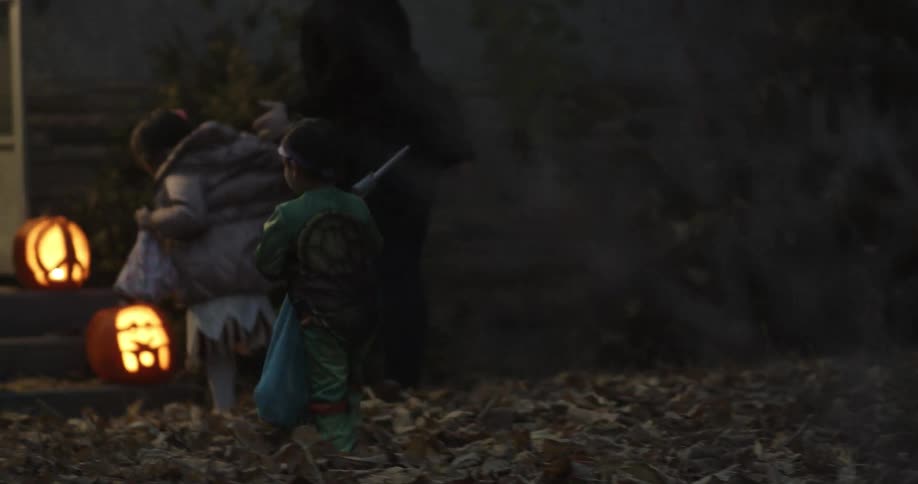A young boy catches up to other children as they are trick-or-treating