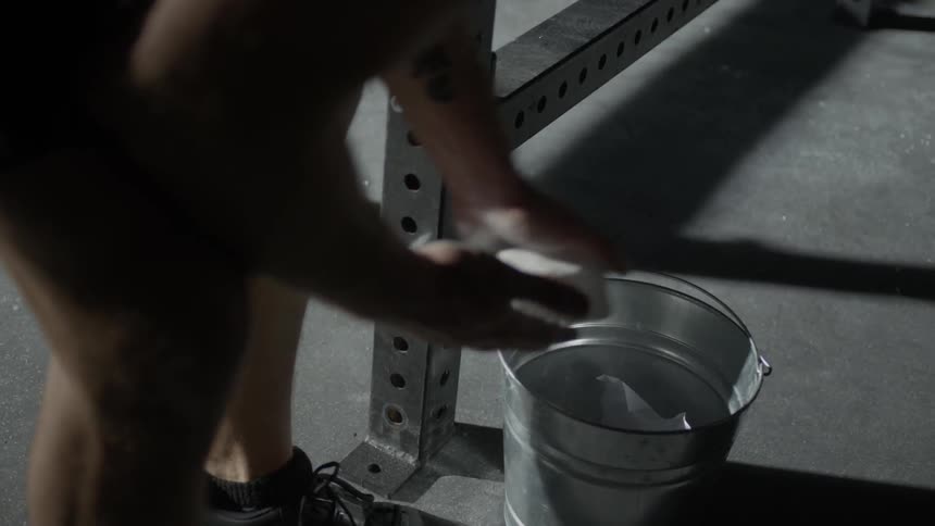 A weightlifter rubs chalk on his hands