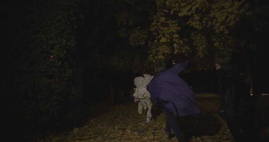 Children run outdoors in halloween costumes