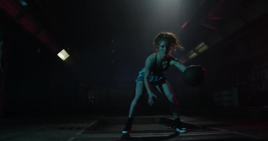 Woman with long hair bounces a basketball from one hand to the other