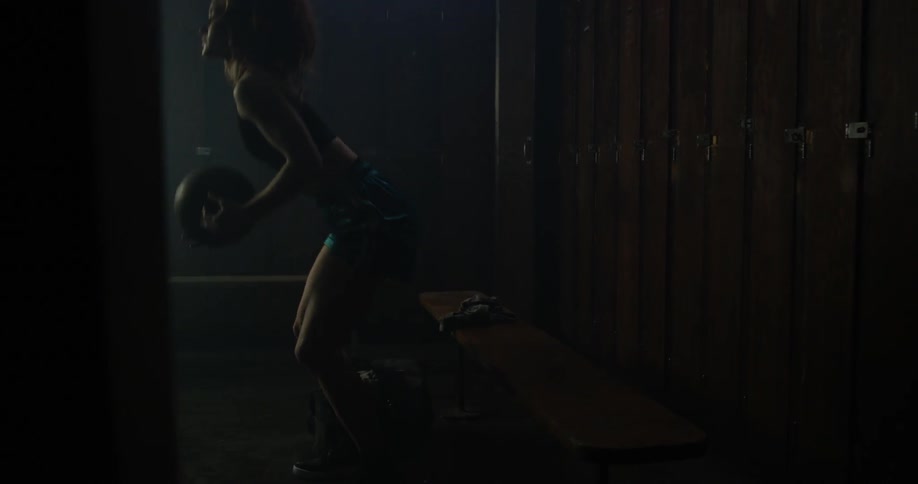 A woman stands up in a locker room with a basketball