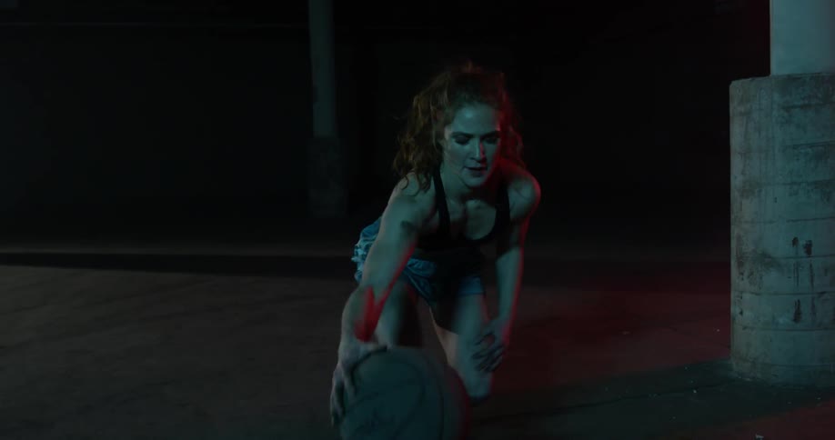 A woman dribbles a basketball between her legs