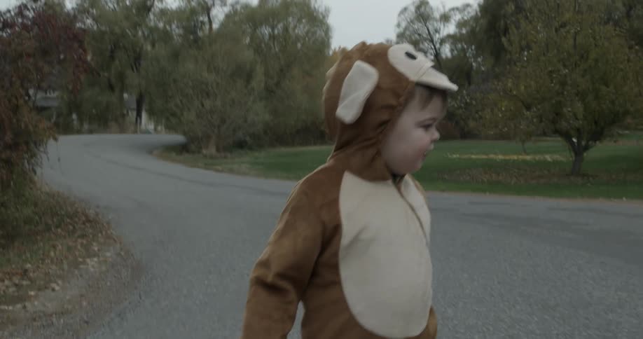 A woman walks a young child to trick or treat