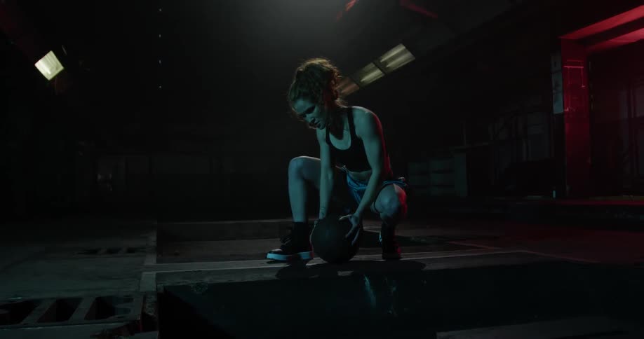 A lady is squatting down holding a basketball