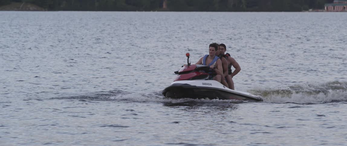 Three people sitting on a speed jet move through the ocean waters